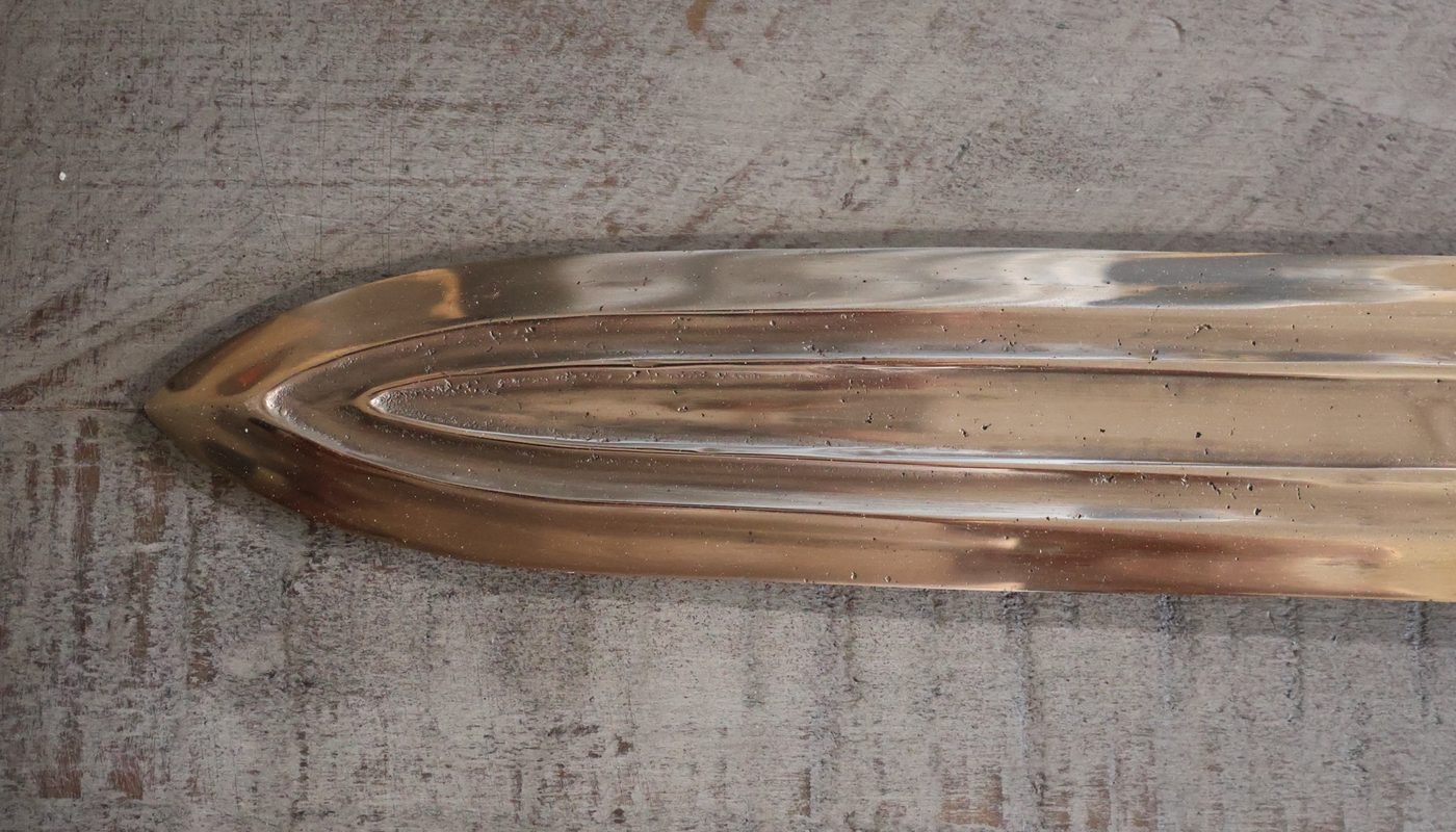 The point of the blade, where the fullers converge and close into a rounded leaf-shaped tip